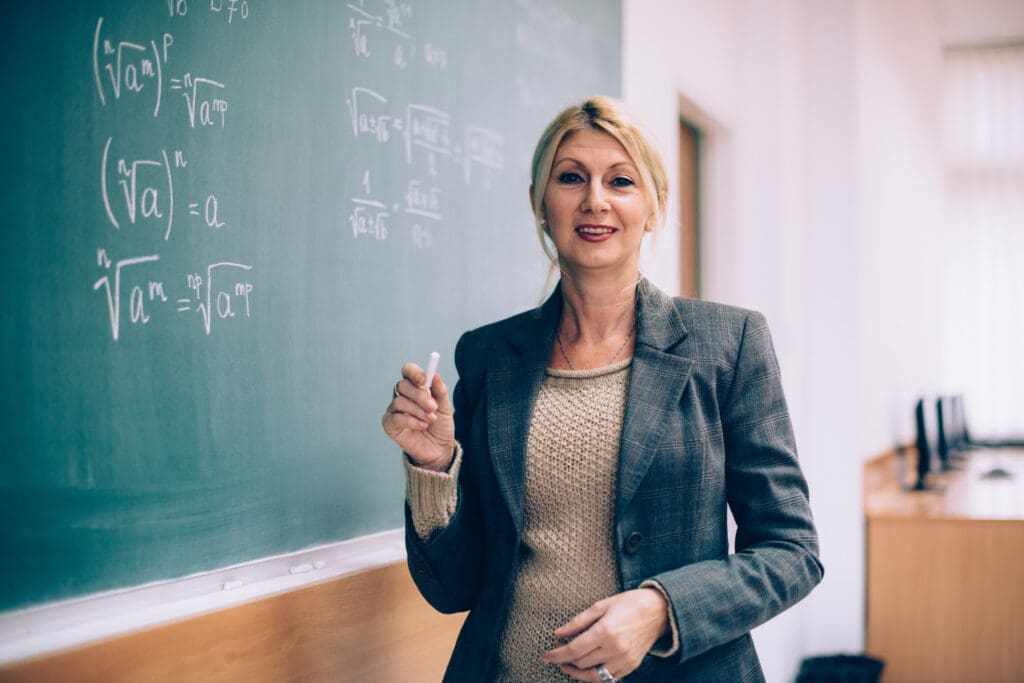 Female math teacher writing equations on chalkboard